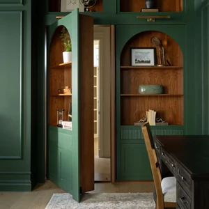 Green built-in shelves with arched niches include a concealed door that opens to a hallway.
