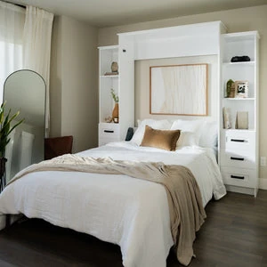 White Murphy bed with built-in side shelves and drawers, shown open in a cozy bedroom.