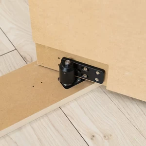 Close-up of a concealed pivot hinge hardware kit installed at the base of a hidden door.