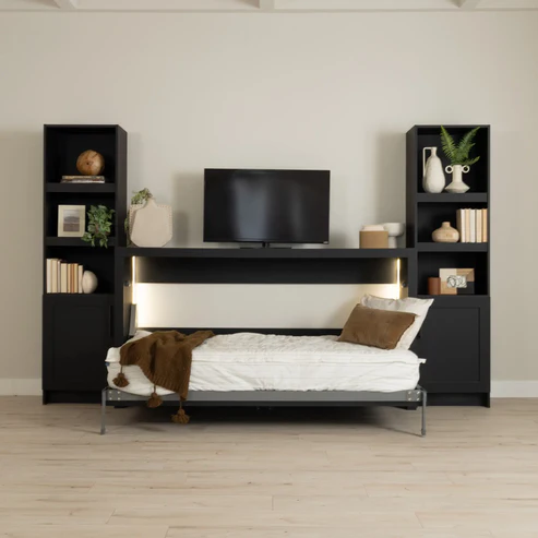 Murphy Door® wall bed unit with black bookcase shelving, white mattress, brown throw, and mounted TV in modern minimalist style.