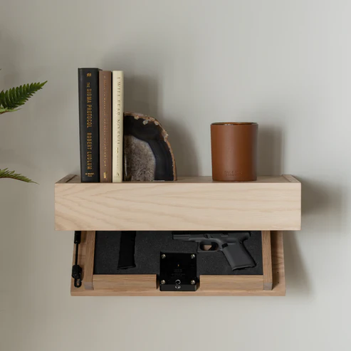 Murphy Door® concealed shelf with handgun storage drawer, featuring light wood construction, books, agate bookend, and brown leather container.