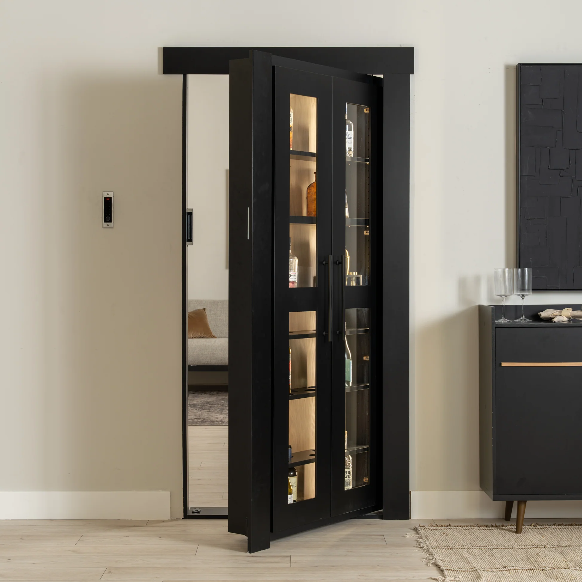Murphy Door® black bookcase hidden door with glass panels, illuminated shelving for bottles, modern home bar storage solution.